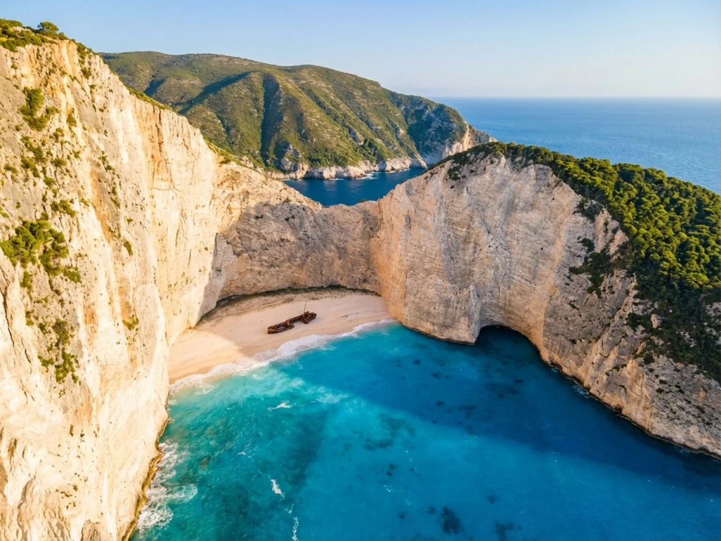 Aerial view of Navagio Beach, Zakynthos showing famous shipwreck on white sand cove surrounded by turquoise waters and cliffs