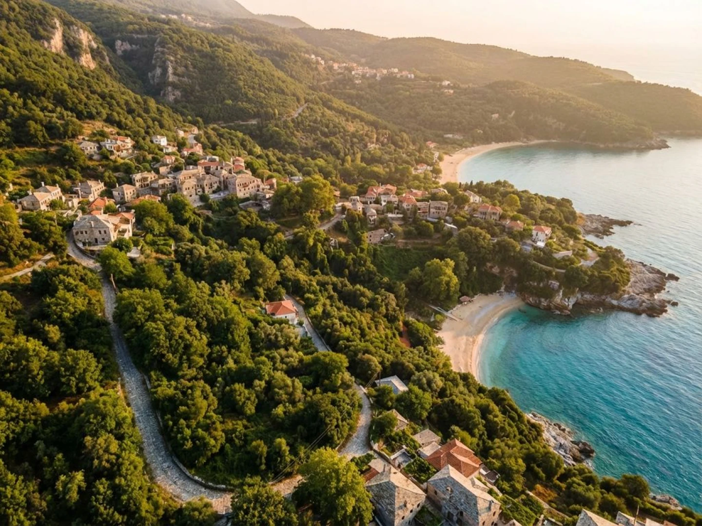Aerial view of Mount Pelion's forested slopes meeting turquoise Aegean Sea waters with traditional Greek villages and beaches