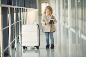 Little girl visiting Greece at the airport with buggage and passport